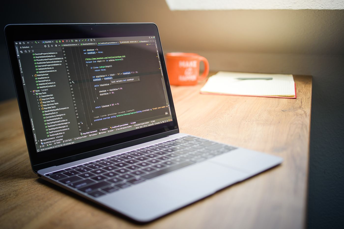 Laptop displaying code beside a notebook on a desk