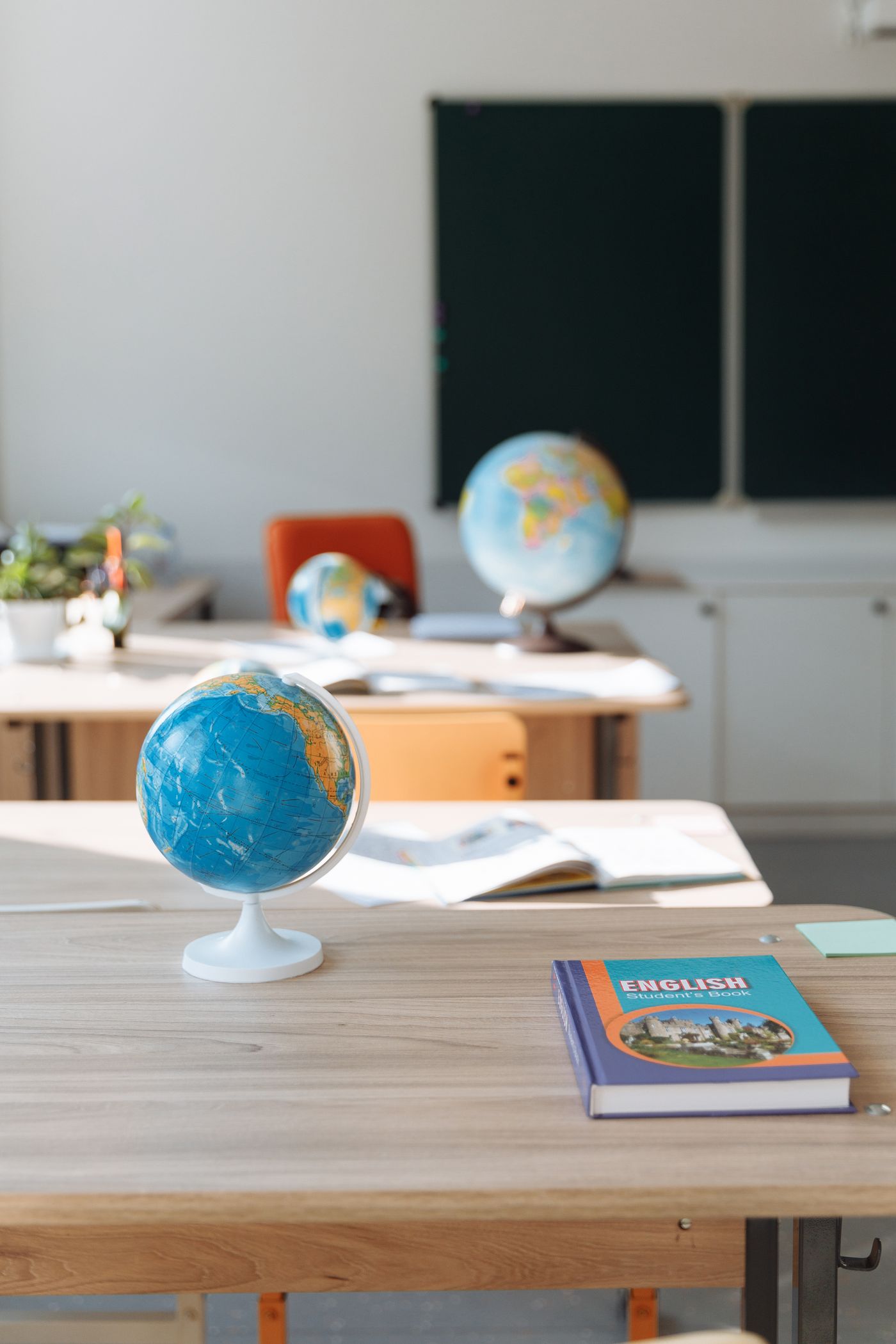 Globes and open textbooks arranged on classroom desks